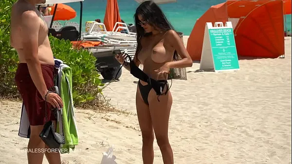 exibindo seus peitos grandes na praia com o marido esperando